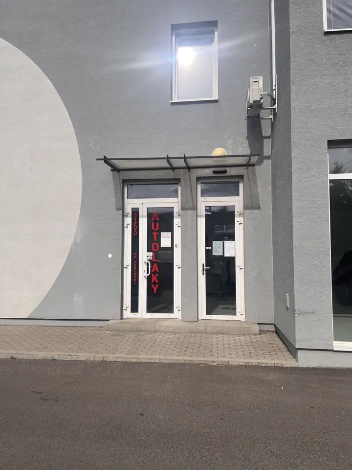 Vchod do budovy s červeným nápisom AUTOLAKY na dverách